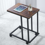 Wooden side table with wheels, tablet, and plant on a white floor.| Artisansa SA
