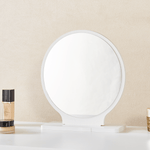 Close-up of freestanding round mirror on white dressing table