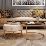 Rose gold nesting coffee table set in living room with cream tufted sofa, yellow flower vase and decorative books