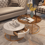 Sintered stone and rose gold nesting coffee table set with amber glass top and cream drawer, front view in luxury living room