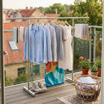Double Rail Retractable Clothes Rack with clothes hanging and accessories on a balcony.