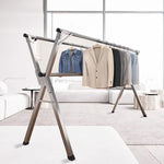 Foldable Clothes Rail featuring stainless steel X-frame with mounted garments in a modern living room.