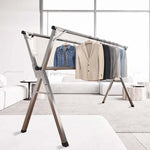 Foldable Clothes Rail featuring stainless steel X-frame with mounted garments in a modern living room.