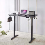Electric Standing Desk in black with laptop and speaker, showcasing adjustable height for ergonomic comfort.