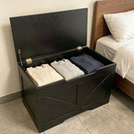 Rustic Wooden Storage bench with folded clothes inside, placed beside a bed, showcasing its organizational capability.