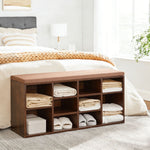 Cubby Shoe Storage Bench with Cushion & Adjustable Shelves placed in a bedroom, storing neatly folded towels.