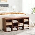 Cubby Shoe Storage Bench with Cushion & Adjustable Shelves placed in a bedroom, storing neatly folded towels.