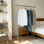 Double Rail Retractable Clothes Rack with Wheels displaying white shirt and jeans in a stylish bedroom setting.