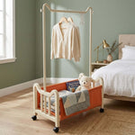 Steel Clothing Rack with Shelves & Wheels showcasing a cozy bedroom with clothing, blankets, and a teddy bear.