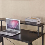 Modern computer desk with power outlets, featuring a laptop and stacked books on its surface.