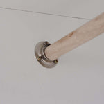 Metal bracket holding a wooden rod against a white ceiling surface, ideal for wardrobe organization.