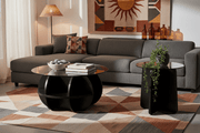 A round glass coffee table set with a black wooden frame, for a modern South African living room.