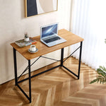 Minimalist Computer Desk with X-Frame Design featuring a laptop, coffee cup, and plant on a stylish wooden surface.