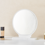 Close-up of freestanding round mirror on white dressing table