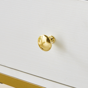 Close-up of polished gold drawer knob on white dressing table