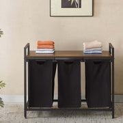 3-Compartment Laundry Sorter with Wood Shelf featuring three black hampers and folded towels.