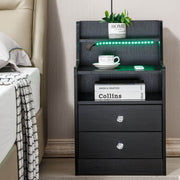 LED nightstand bedside table with green LED lights and storage drawers beside a bed.