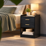 Black two-drawer bedside table styled in a warm modern bedroom