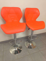 Set of 2 Retro Style Bar Chairs with vibrant orange seats and chrome bases on grey floor.