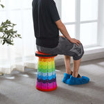 Person sitting on colourful stack of retractable telescopic foot stool KJ-01 indoors | Artisansa SA