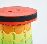 Colourful plastic retractable telescopic foot stool KJ-01 with red top, black band, orange middle, and green base on light gray background | Artisansa SA