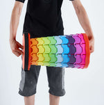 Person holding colourful cylindrical object with gradient colours - retractable telescopic foot stool KJ-01 demonstration | Artisansa SA