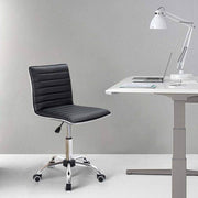 Adjustable bar stool set in ergonomic black PU leather beside a modern desk with lamp and laptop.