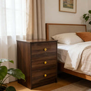 Modern 3-Drawer Nightstand with gold handles beside a cozy bed in a bright bedroom setting.