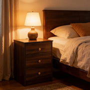Modern 3-Drawer Nightstand with gold handles beside a cozy bed and lamp, showcasing minimalist design.