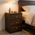 Modern 3-Drawer Nightstand with Gold Handles beside a bed in a cozy bedroom setting.