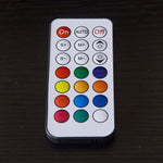 Remote control with various colored buttons for adjusting settings and functions.