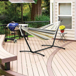 Double Hammock with Steel Stand on a wooden patio beside a BBQ grill and small table with flowers.