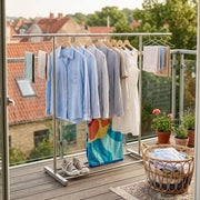 Double Rail Retractable Clothes Rack with clothes hanging and accessories on a balcony.