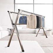 Foldable Clothes Rail featuring stainless steel X-frame with mounted garments in a modern living room.