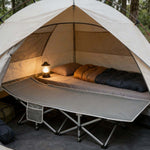 Two folding camping cots with mattresses placed together inside camping tent