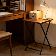Rustic folding TV tray table next to a modern desk with lamp and storage box, perfect for maximizing space.