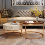 Rose gold nesting coffee table set in living room with cream tufted sofa, yellow flower vase and decorative books