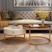 Rose gold nesting coffee table set in living room with cream tufted sofa, yellow flower vase and decorative books