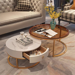 Sintered stone and rose gold nesting coffee table set with amber glass top and cream drawer, front view in luxury living room