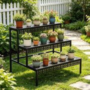 Tiered black metal plant stand displaying small and medium pots beside a garden path