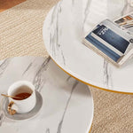 Top view of white marble-effect nesting tables with a cup, book and gold trim
