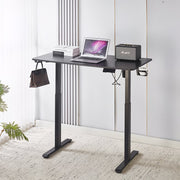 Electric Standing Desk in black with laptop and speaker, showcasing adjustable height for ergonomic comfort.