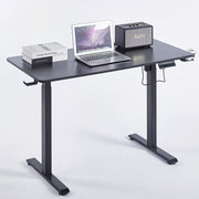 Electric Standing Desk in black with laptop, books, and speaker showcasing ergonomic design for modern workspaces.