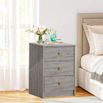Modern 3-Drawer Nightstand featuring gold handles, styled beside a bed in a bright room.