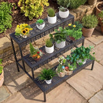 Top-angle view of black 3-tier plant stand with herbs, flowers and decorative pots