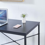 Close-up of black desktop surface with laptop, phone and reinforced cross-braced frame