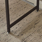 Close-up of the sturdy leg and support bar of a modern computer desk on a textured carpet.