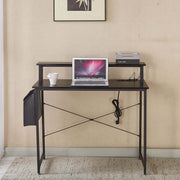 Modern computer desk with power outlets, laptop on top, coffee cup, and books in a home office setting.