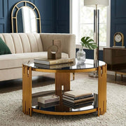 Round Glass Coffee Table with gold geometric frame and black glass, styled with books and decor in modern lounge setting.
