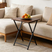 Rustic folding TV tray table with a plate of fruits, placed beside a cozy couch.
